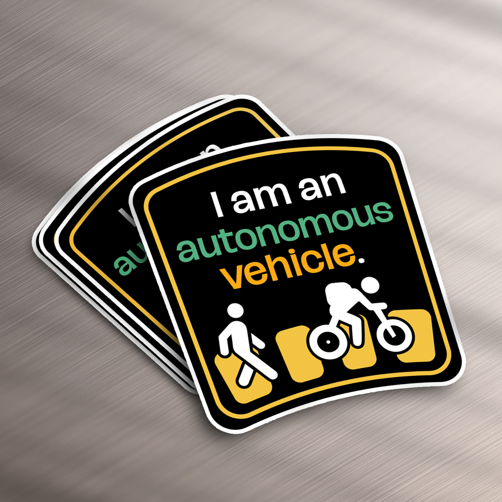 Design As A Service 16 These stickers, perfect for a design subscription, flaunt a traffic-themed motif with I am an autonomous vehicle in white, green, and orange. Below this text, icons depict a pedestrian, cyclist, and car against a black backdrop framed in white.